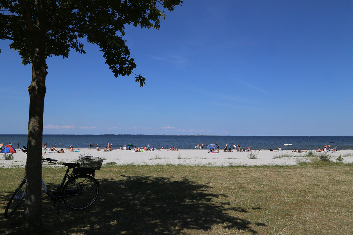 Udsigt over Bandholm Strand, hvor mennesker solbader